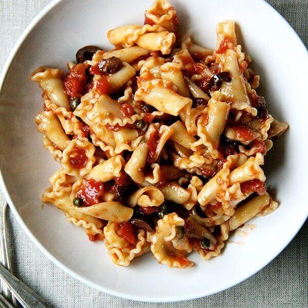 A bowl of pasta tossed with puttanesca sauce.