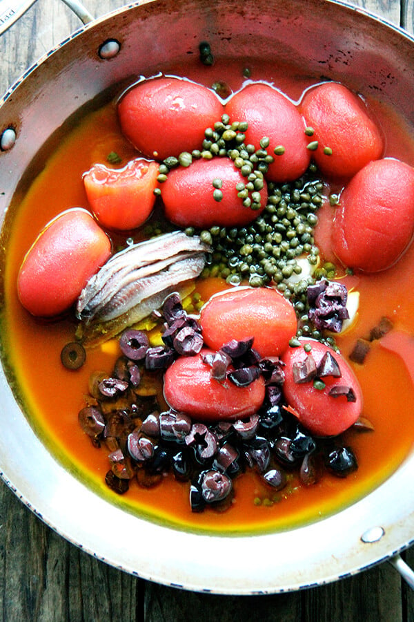 A sauté pan filled with the ingredients for puttanesca sauce.