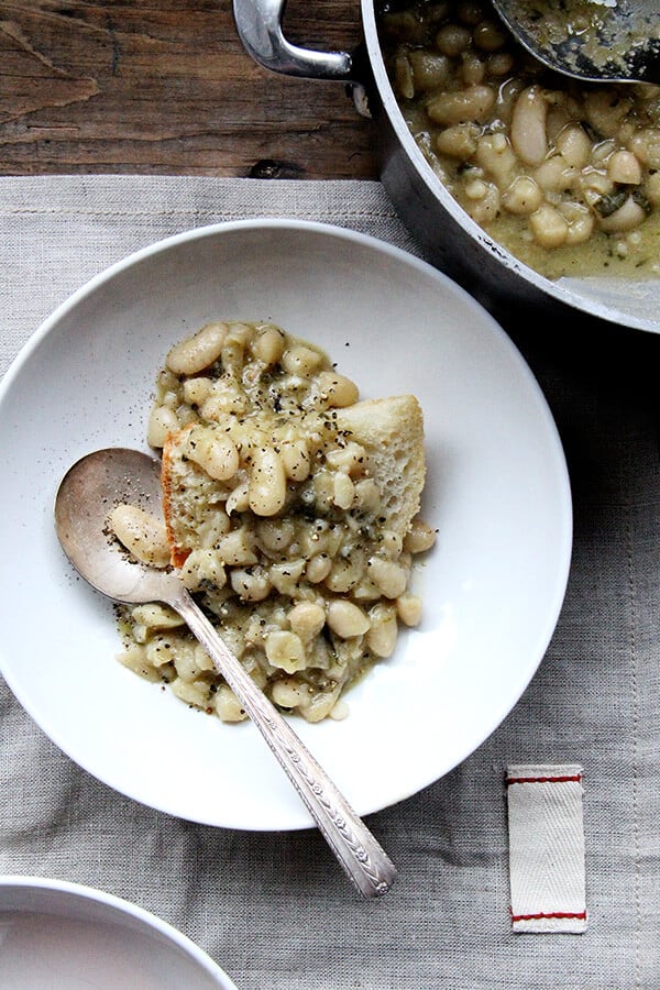 A bowl of stewy white beans and breaad