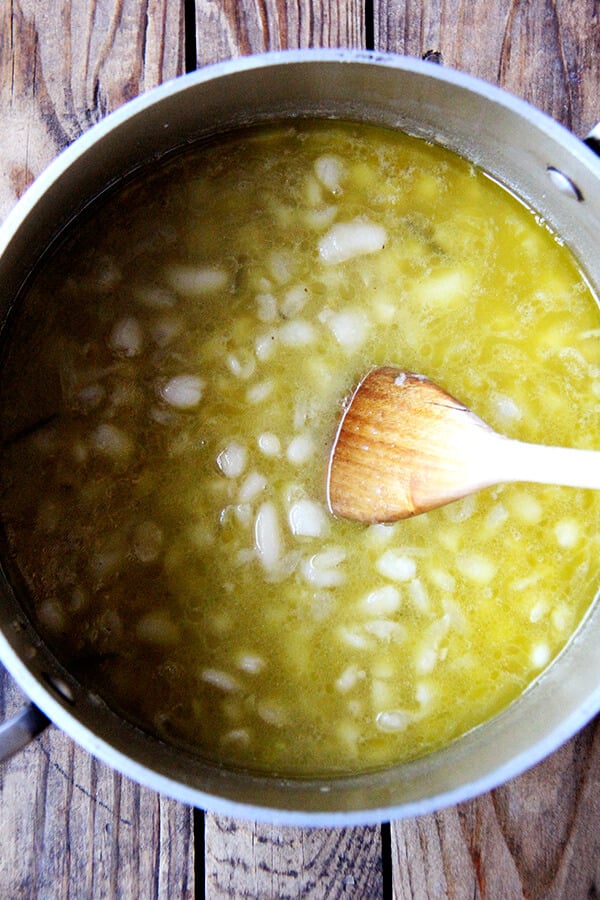 brothy white beans in a pot with a spoon