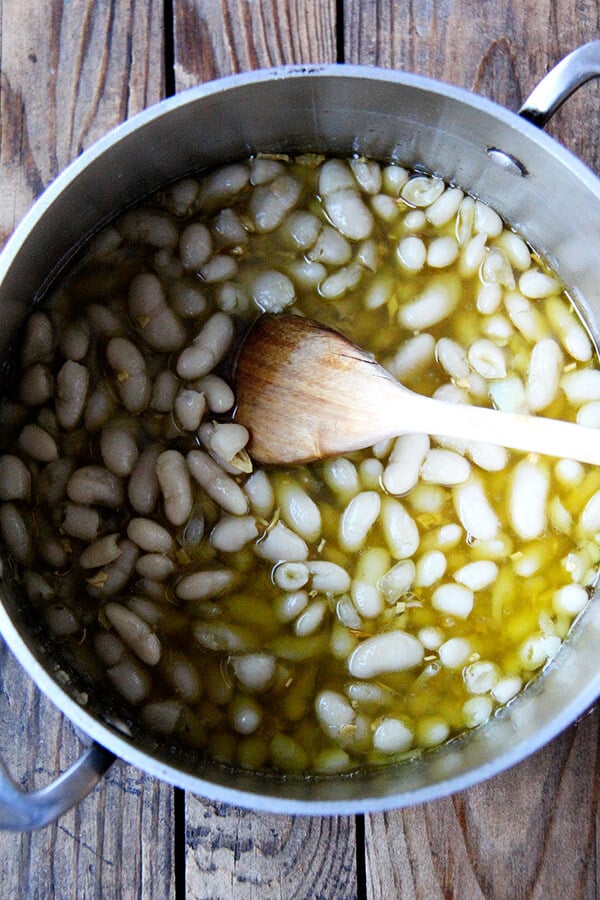 white beans and olive oil in a pot with a spoon