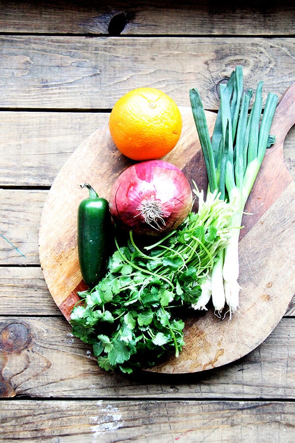 A board of cilantro, red onion, orange, scallions, and jalapeno.