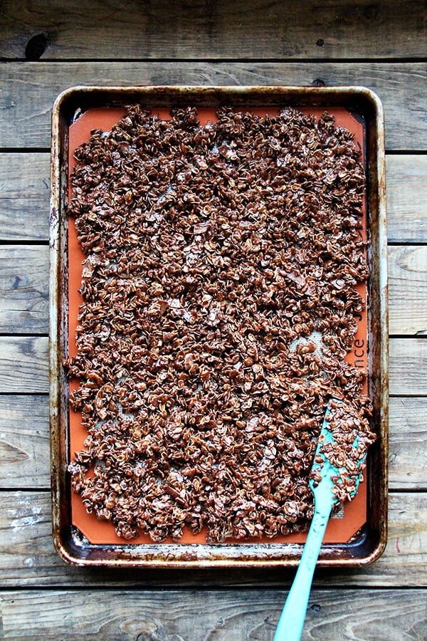 A sheet pan of cocoa crunch spread onto silpat, unbaked.