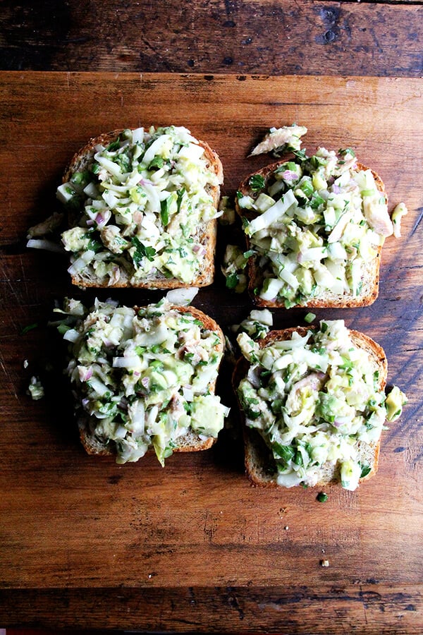 Four open-face toasts topped with smoked trout and avocado salad. 
