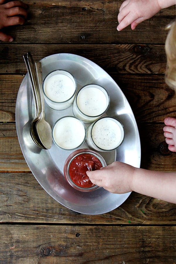 Overhead shot of panna cotta and children reaching in. 