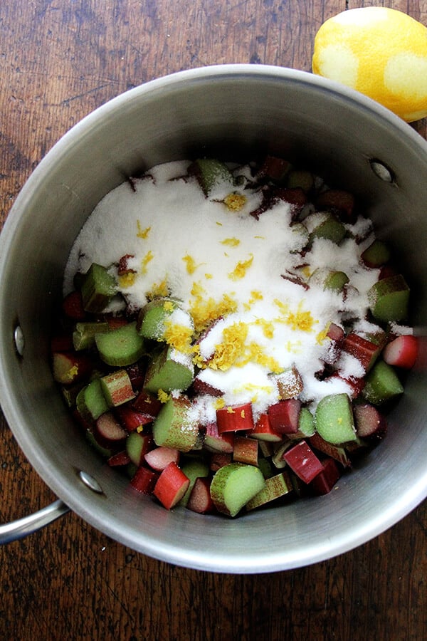 A pot with rhubarb, sugar, and lemon zest.