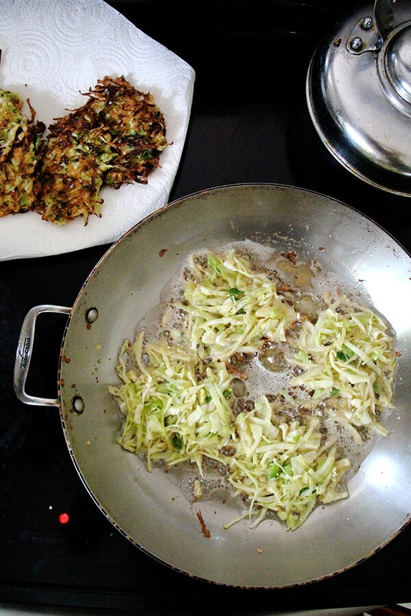 frying the cabbage pancakes in a large skillet