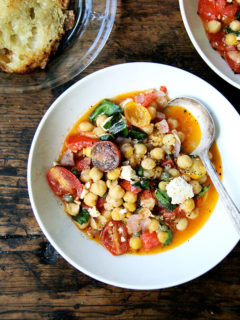 A bowl of stewy chickpeas with tomatoes and feta.