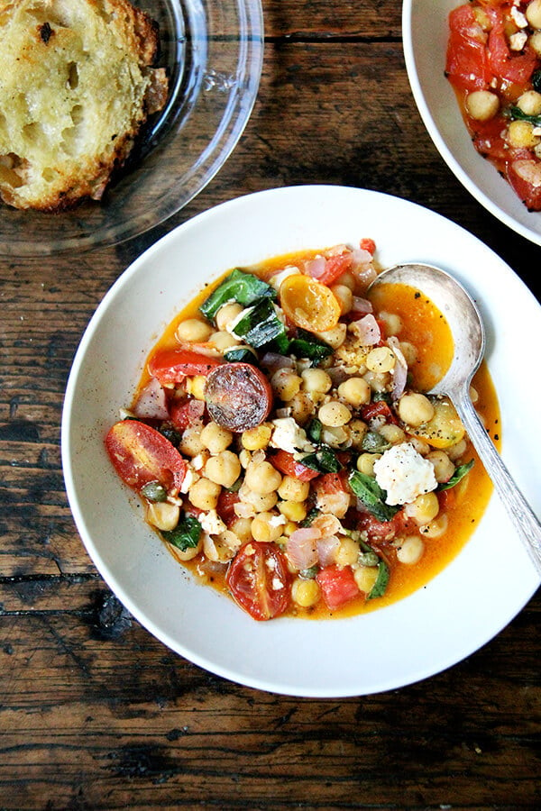 A bowl of stewy chickpeas with tomatoes and feta.