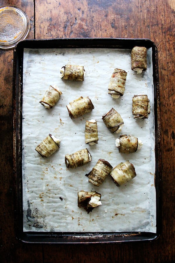 Eggplant involtini rolled up on a sheet pan.