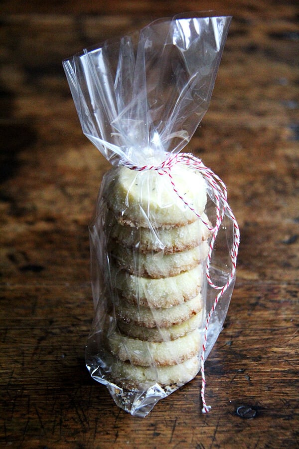 A stack of vanilla bean sablé cookies tucked in a cellophane bag, tied with baker's twine.