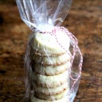 A stack of vanilla bean sablé cookies tucked in a cellophane bag, tied with baker's twine.