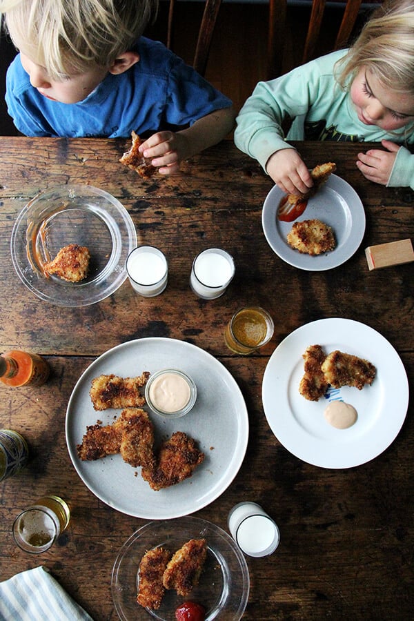 Kids eating baked chicken fingers.