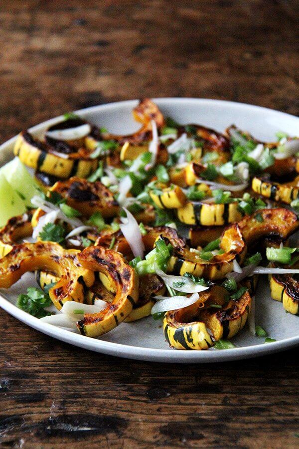 Roasted delicata squash on a platter topped with chilies, lime, and cilantro.