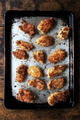 A sheet pan of baked chicken fingers.