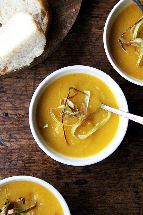 Bowls of butternut squash and apple soup topped with crispy leeks.