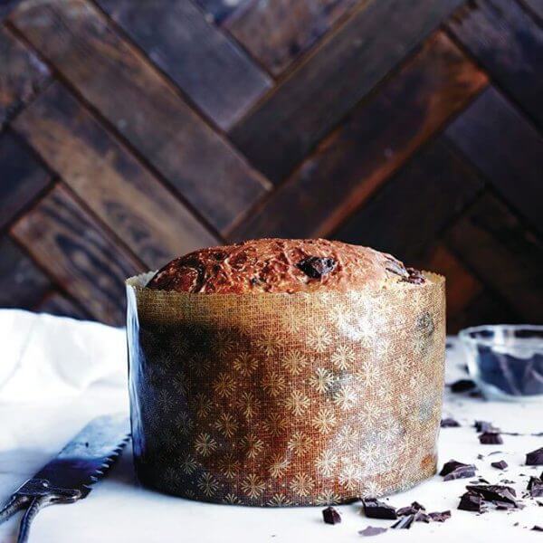 Baked chocolate-studded panettone bread recipe wrapped in large paper mould.