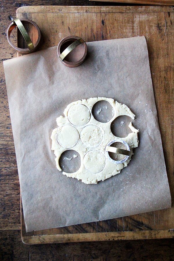 Classic Cream Cheese Cut-Out Cookie dough on a cutting board, rolled out on parchment paper with biscuit cutters nearby. 