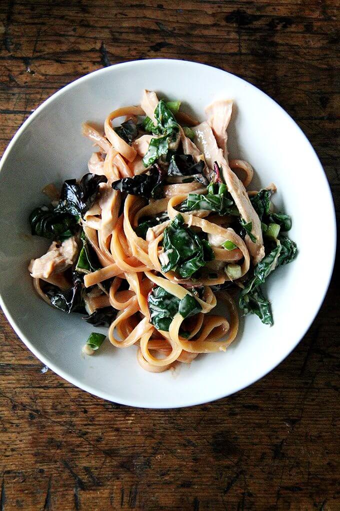 A bowl of sesame noodles with Swiss chard. 