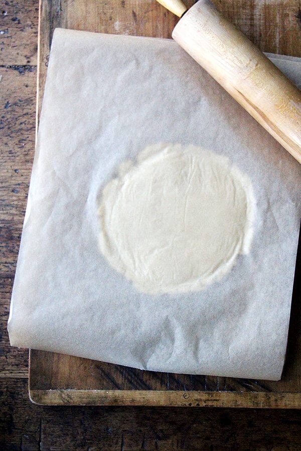 Rolling out the classic cream cheese cutout cookie dough between two sheets of parchment paper. 