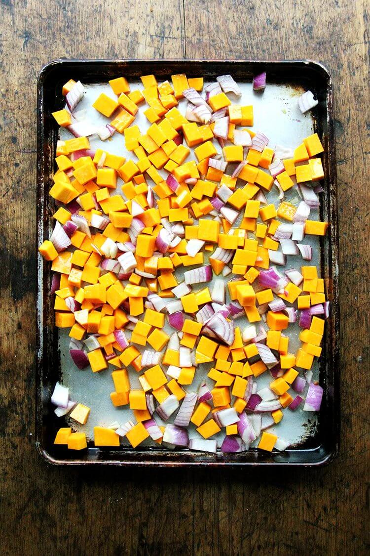 A sheet pan of cubed squash and onion ready to be roasted. 