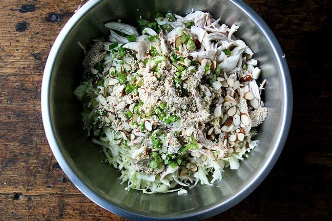 A large bowl with the ingredients to make chicken and cabbage salad ready to be tossed.