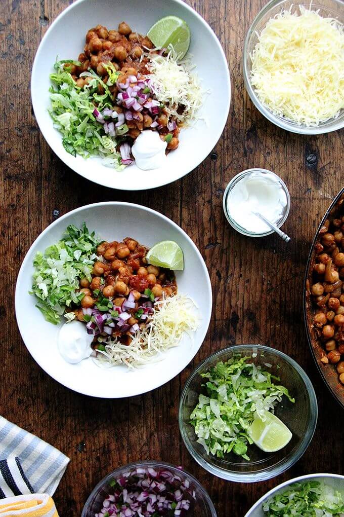 Assembled chickpea taco bowls with lettuce, lime, sour cream, and cheese.