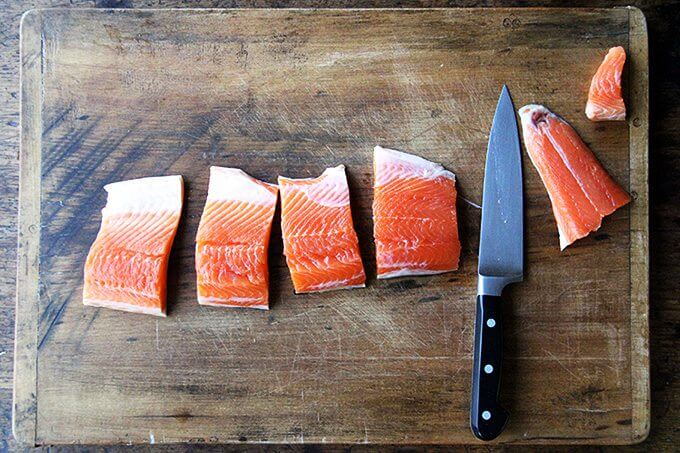 A board with arctic char on top, cut into filets. 