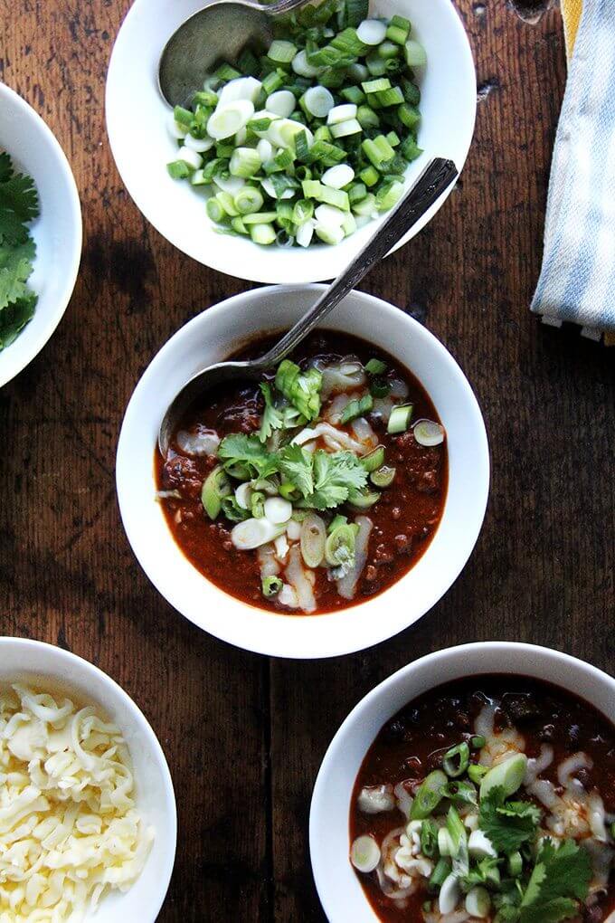 A few bowls of weeknight chili with assorted toppings. 