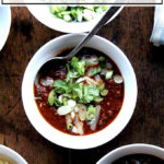 A bowl of weeknight chili topped with scallions, grated cheese, and cilantro.