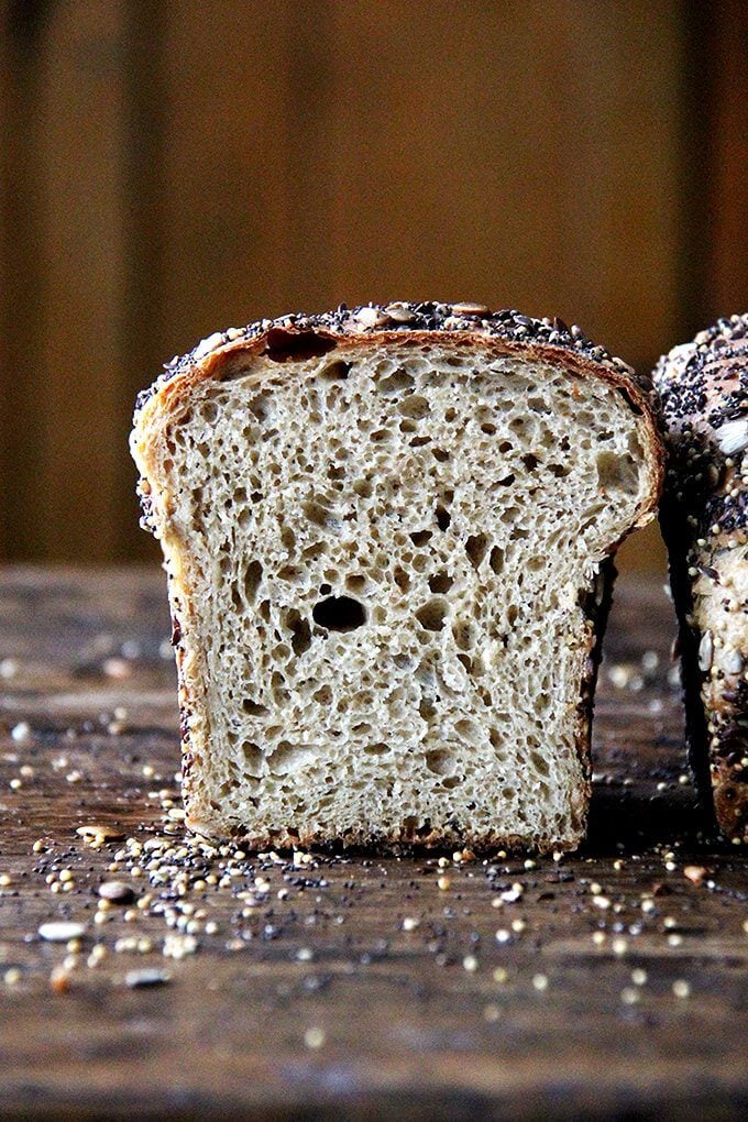 A halved loaf of seedy sandwich bread.