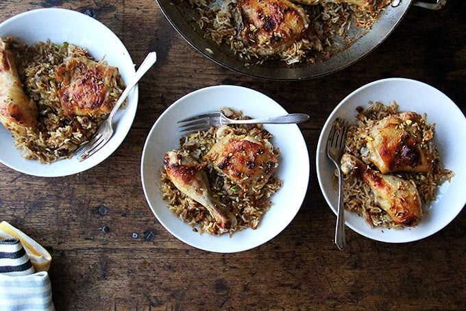 Overhead shot of three bowls of Moroccan chicken and rice with forks. 