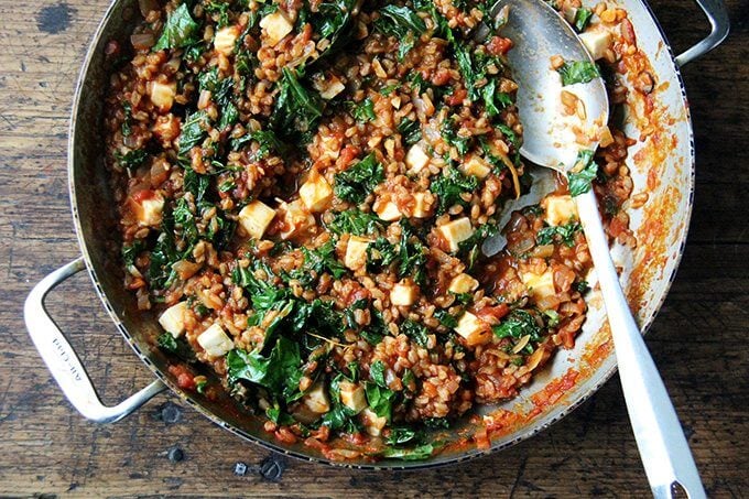 Overhead shot of finished farro risotto in sauté pan with spoon. 