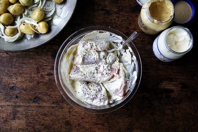 A bowl of chicken thighs tossed in a mixture of mayonnaise and mustard.