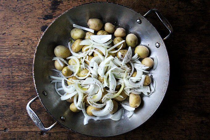 A braiser filled with potatoes and onions.