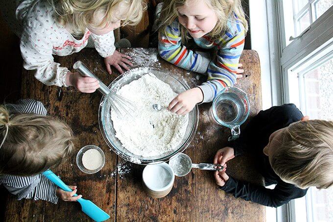 Overhead shot of children whisking together the pizza dough. 