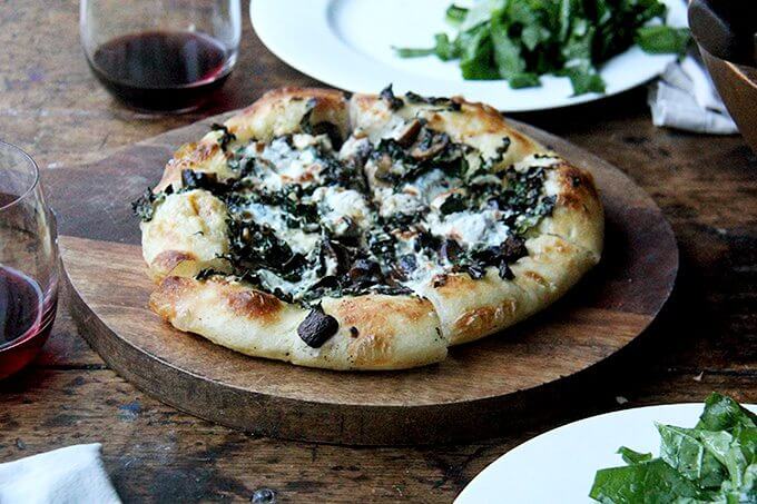 A kale and mushroom skillet pizza on a board. 