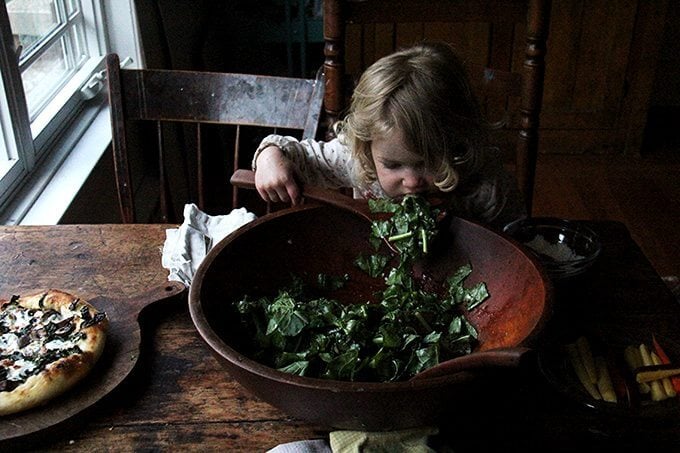 Toddler eating kale salad straight from the bowl. 