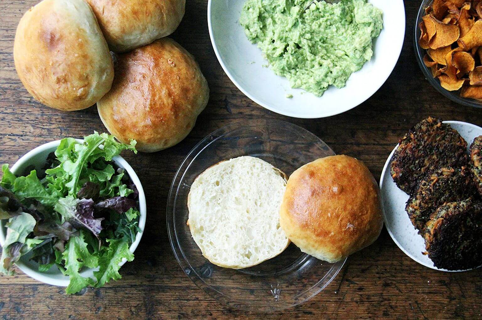 A board filled with homemade brioche buns, mashed avocado, and mushroom-quinoa burger patties.