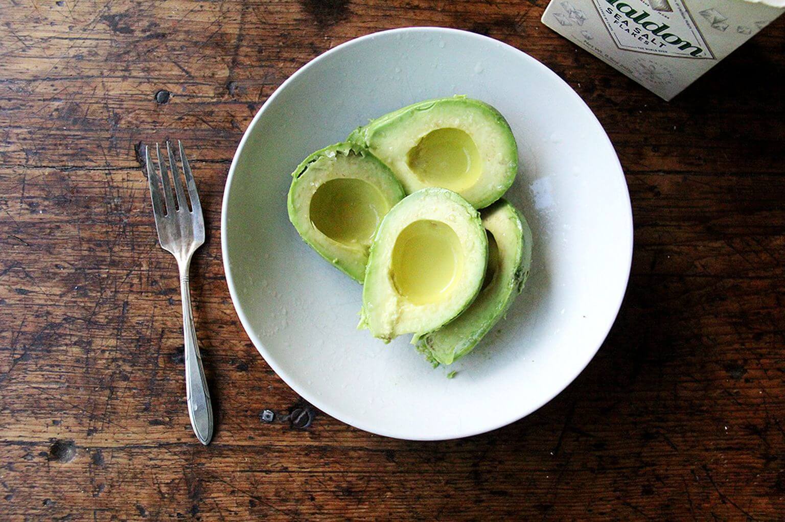 A bowl of two avocados. 