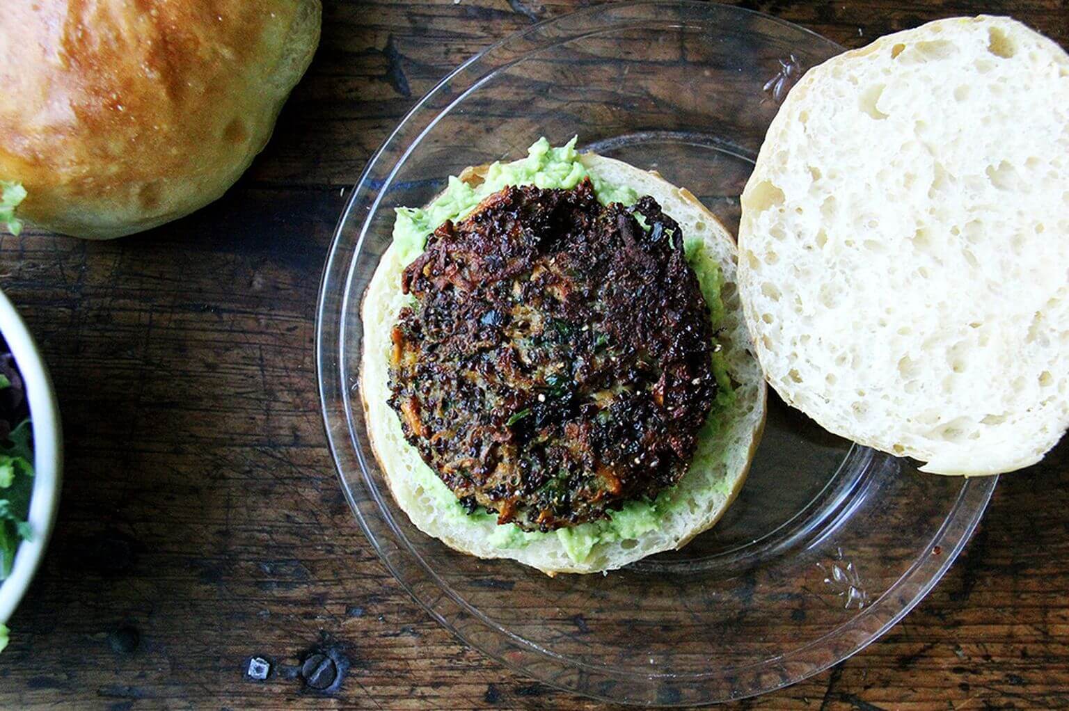 Overhead shot of open-face veggie burger on a brioche bun with mashed avocado.