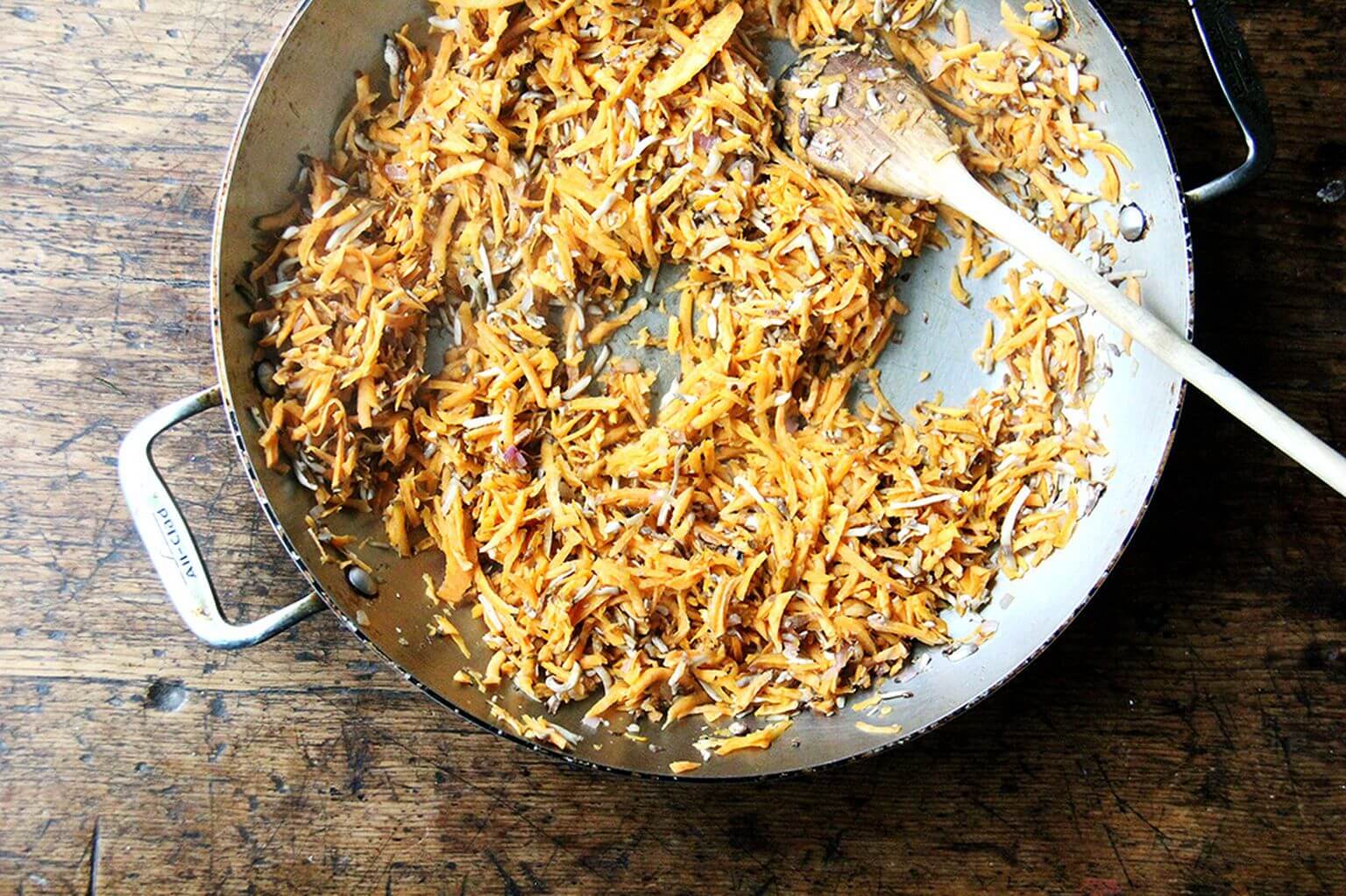 A skillet with sautéed sweet potato and mushrooms.