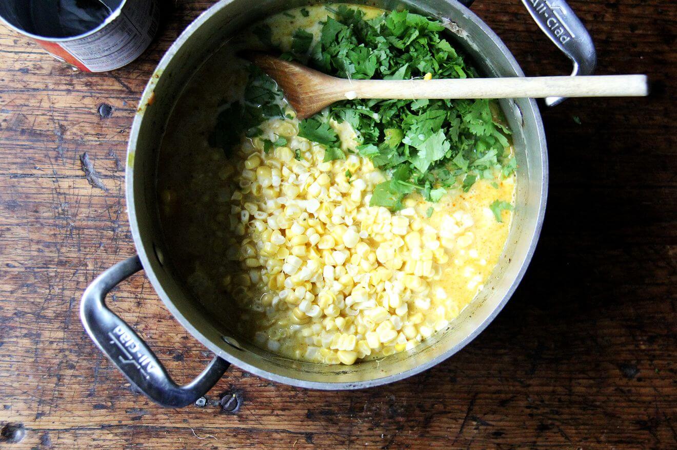 A pot filled with curried corn soup and cilantro.