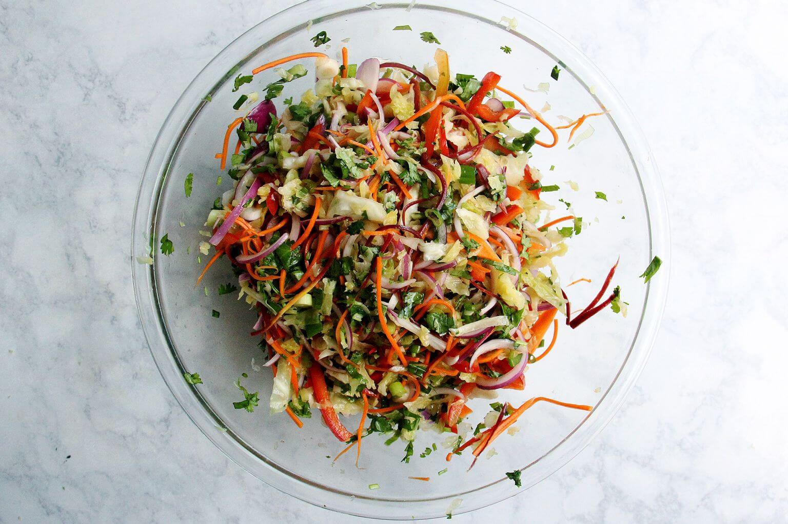 A large bowl filled with tossed Thai chicken and cabbage Salad. 
