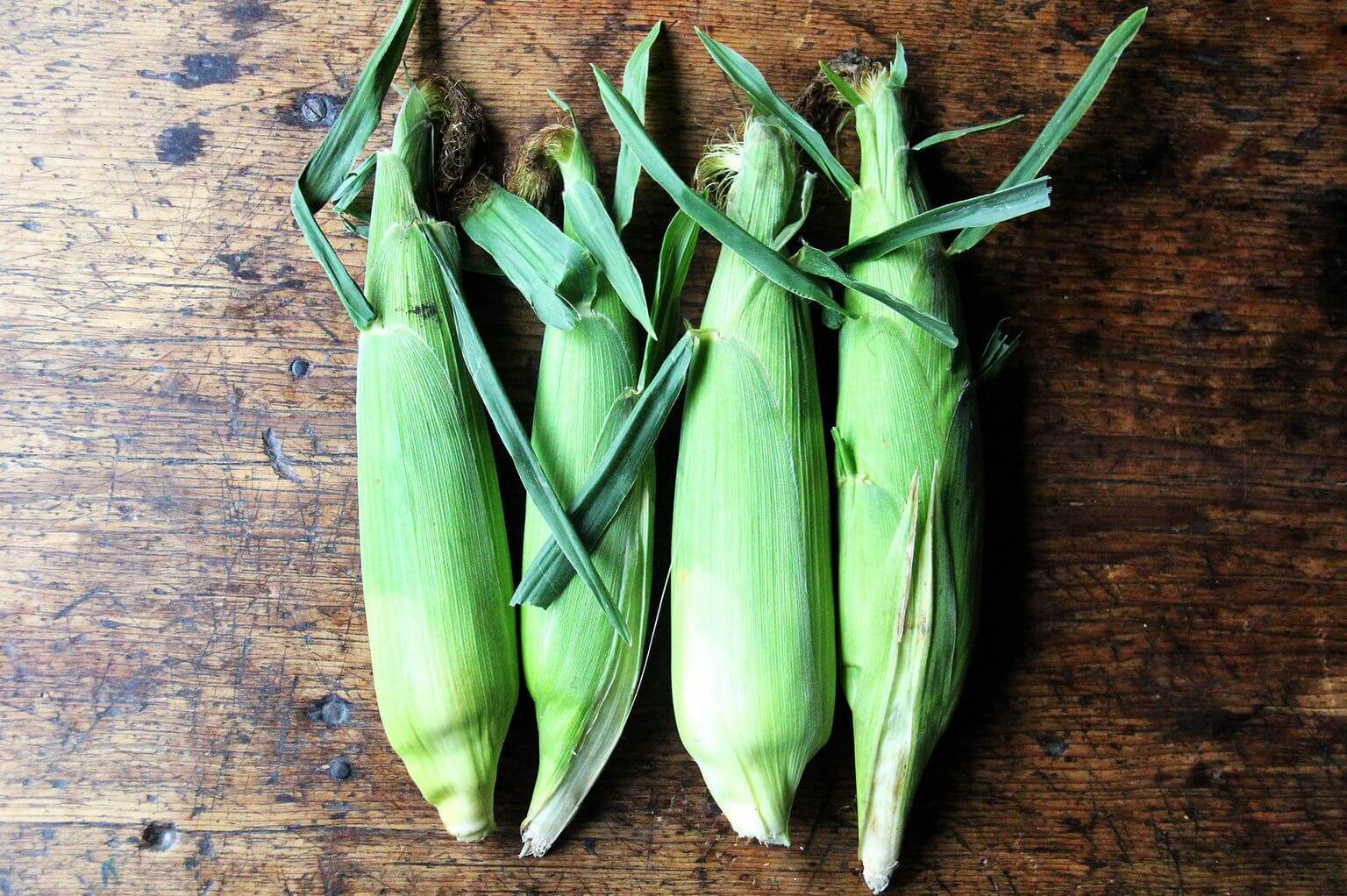 4 ears of corn on a board.