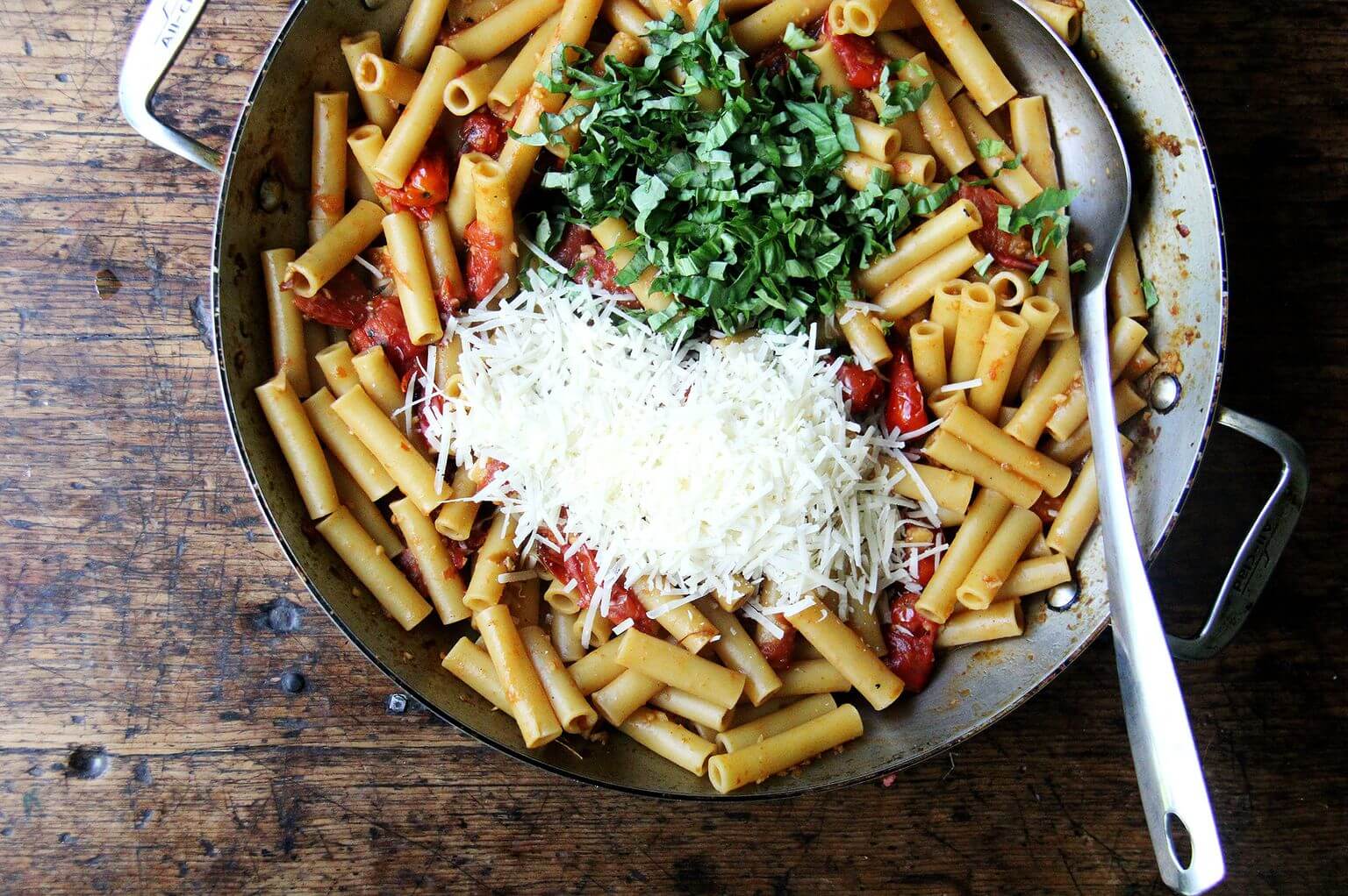 A large skillet with ziti, parmesan, and basil.