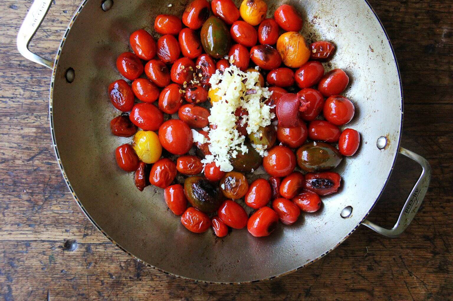 A large skillet with tomatoes and garlic.