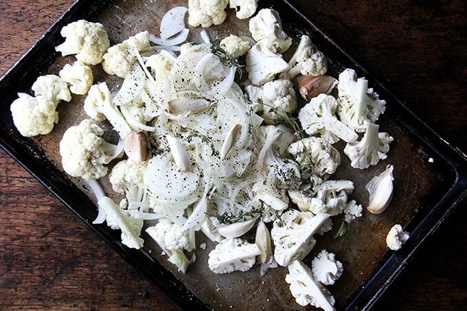 A sheet pan of cauliflower, onions, garlic, and thyme, not yet roasted. 