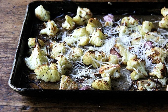 Oven-roasted cauliflower florets on a sheet pan sprinkled with parmesan.