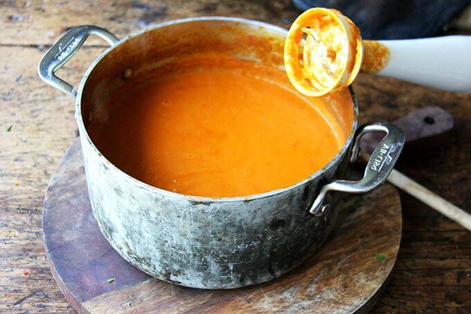 A pot of puréed tomato sauce aside an immersion blender.